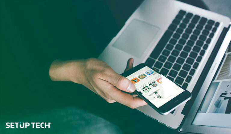 Pessoa a segurar o telemóvel com o computador como fundo - artigo como criar uma app no play store