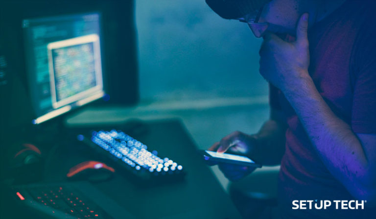 Programador a mexer no telemóvel com computador desfocado no fundo - post como criar aplicativo android