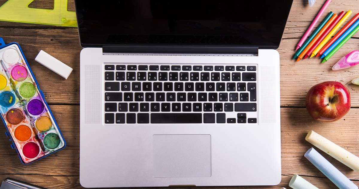 Artigo jogos educativos - mesa de escola com lápis, réguas, etc e um computador